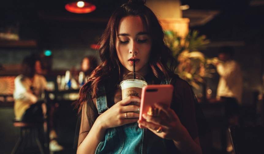 Girl drinking ice coffee studying on her phone